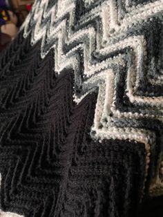 a black and white crocheted blanket sitting on top of a bed