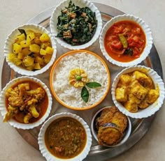 a plate full of different types of food on top of a metal tray with white rice and sauces