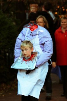 a man dressed as a child with blood all over his face and apron on walking down the street