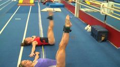 two people are doing exercises on the floor in an indoor gym area with blue carpet