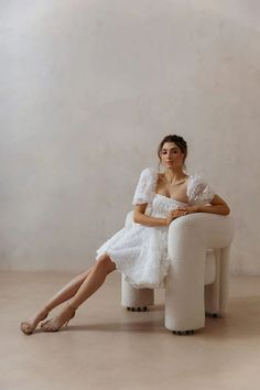 a woman is sitting on a white chair