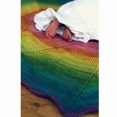 a baby laying on top of a rainbow blanket