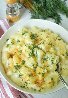 a white bowl filled with macaroni and cheese on top of a red and white table cloth