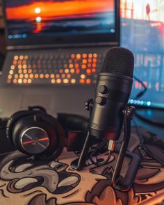 a microphone and headphones on a desk in front of a computer screen with a laptop