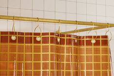 an orange and yellow checkered shower curtain hanging from a gold metal rod in a bathroom