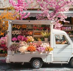 a white truck parked in front of a store filled with lots of pink and yellow flowers