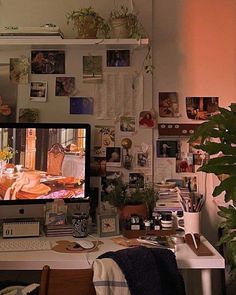 a computer monitor sitting on top of a desk next to a potted green plant