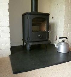 a stove with a tea kettle sitting on top of it next to a brick wall