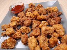 fried food on a plate next to a small bowl of ketchup and sauce