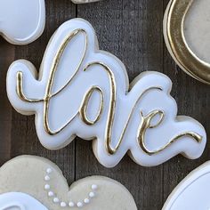 decorated cookies with the word love spelled in gold on top of each cookie, surrounded by other white and gold decorations