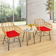 three wicker chairs and a table in a room with wood flooring, large windows and potted plant