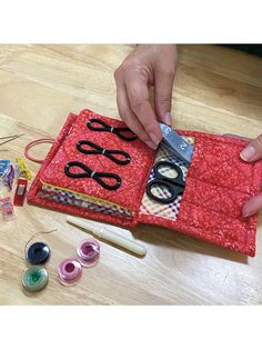 a person cutting fabric with scissors and sewing thread on a table next to some crafting supplies