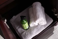 a bottle of shampoo sitting on top of a white towel next to a green sprayer