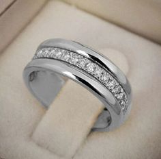 a wedding ring with three rows of diamonds on it in a white velvet box,