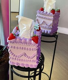 two cakes with strawberries on them sitting on top of stools next to each other