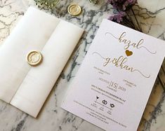 the wedding stationery is laid out on top of the marble table with gold buttons