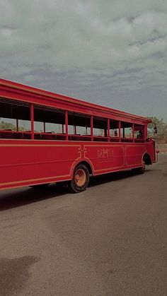 an old red bus is parked on the side of the road