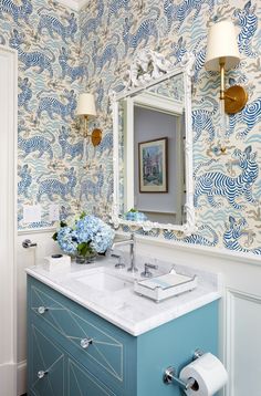 a bathroom with blue and white wallpaper, a vanity sink and two lights above it