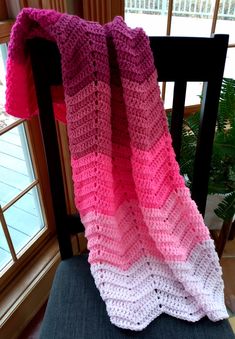 a pink and white crocheted blanket sitting on top of a chair