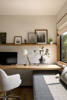 a room with a desk, chair and computer on the wall next to a window