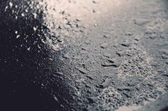 water drops on the surface of a black table with white dots and blue sky in the background