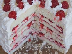 a cake with white frosting and raspberries is cut in half to show the layers