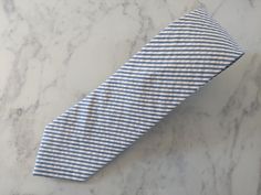 Upgrade your wardrobe in style with our handmade blue seersucker tie. This stunning tie measures 5cm at the widest point and is guaranteed to enhance any outfit. Perfect summer gift for him. Dapper Business Ties For Summer, Dapper White Suit And Tie Accessories For Summer, Dapper Suit And Tie Accessories For Summer Business, Summer Business Suit And Tie Accessories, Adjustable, Dapper Blue Suit And Tie Accessories For Summer, Blue Dapper Suit And Tie Accessories For Summer, Striped Summer Tie, Striped Summer Ties, Silk Pocket Square