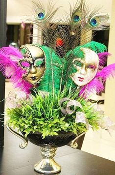 a vase filled with green plants and purple feathers