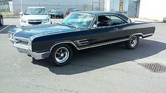 an old black car parked in a parking lot