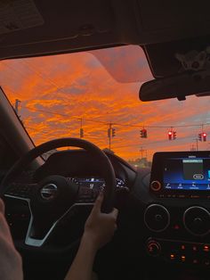 a person driving a car with the sun setting in the background