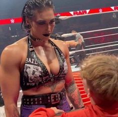 a woman in a wrestling ring talking to a young boy