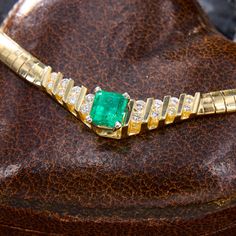 This sleek yellow gold omega necklace is centered with an emerald cut emerald, weighing an estimated 1.72 carats, in a four-prong white gold setting. The emerald is flanked on either side with eight (8) round brilliant cut diamonds, channel set into four (4) rows. The omega chain measures 5.1mm wide, is 17 inches long, and is finished with a hidden box clasp and figure eight safety. The emerald is luminous and the contrast between the color of the emerald and yellow gold omega necklace is fantas Luxury Baguette Cut Emerald Necklace For Formal Occasions, Luxury Baguette-cut Emerald Necklace For Formal Occasions, Luxury Emerald Cut Emerald Necklace For Anniversary, Elegant Emerald Cut Emerald Necklace For Formal Occasions, Formal Fine Jewelry Emerald Necklace With Baguette Cut, Formal Baguette Cut Emerald Necklace In Fine Jewelry Style, Formal Fine Jewelry Baguette Cut Emerald Necklace, Formal Baguette Cut Emerald Necklace, Classic Diamond Cut Emerald Necklace For Formal Occasions