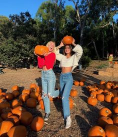 two women are posing with pumpkins in front of them