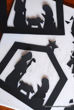 three cut out silhouettes of the nativity scene on a wooden table with black and white paper