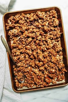 granola in a baking pan with a spoon