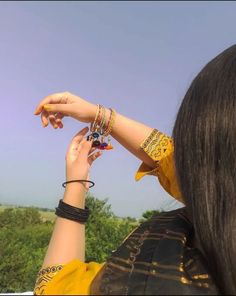 a woman is flying a kite in the sky with her hand on top of her head