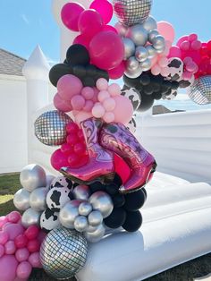 a bunch of balloons that are on top of an inflatable arch with a cowgirl boot