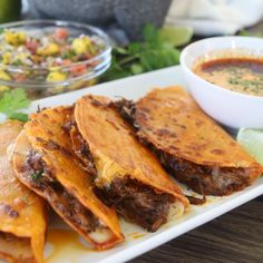 several tortillas on a plate with salsa in the background