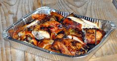 a tin pan filled with chicken wings on top of a wooden table