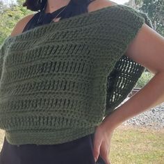 a woman is wearing a green knitted top and has her hands on her hips