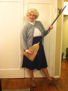 a woman standing in front of a door holding a broom