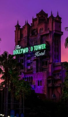 the hollywood tower hotel is lit up at night with palm trees in front of it