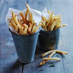 two buckets filled with french fries sitting on top of a wooden table next to each other