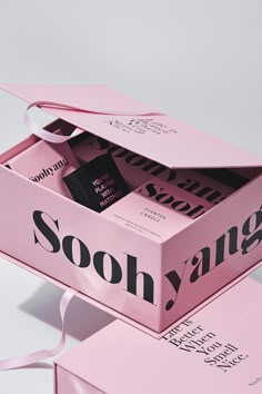 two pink boxes with ribbons on them sitting next to each other in front of a white background