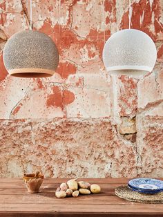 three lamps hanging from the ceiling above a wooden table with plates and bowls on it