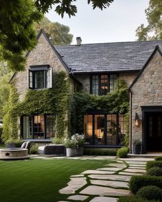 a large stone house with lots of windows and greenery on the front door, surrounded by lush green grass