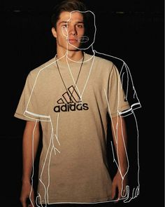 a young man standing in front of a black background wearing a adidas t - shirt