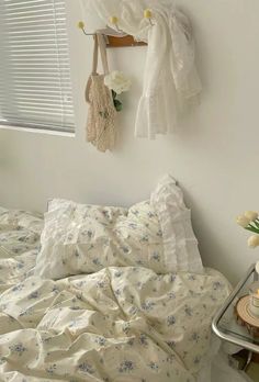 a bed with white sheets and flowers on it next to a wall hanging over the headboard