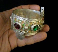 The bracelet is handmade by the Moroccan Berber tribe. The bracelet has a ardillon buckle and a hinge that opens and closes the bracelet for a safe attachment. Unfortunately, it is not adjustable. The bracelet is pure silver and hand-decorated with green and yellow Berber enamel. It is decorated with Berber glass stones and 4 antique pieces. For reference, well see the photos, there is a photo that shows that the bracelet has a red stone whose circumference is not complete, which is silver, and