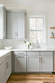 a kitchen with white cabinets and wood floors